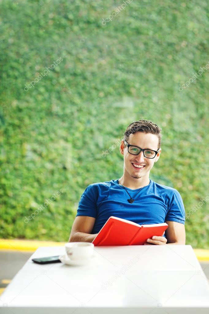 Young man reading a red book at home