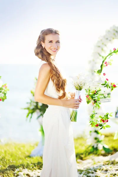 Bella sposa vicino all'arco dei fiori — Foto Stock