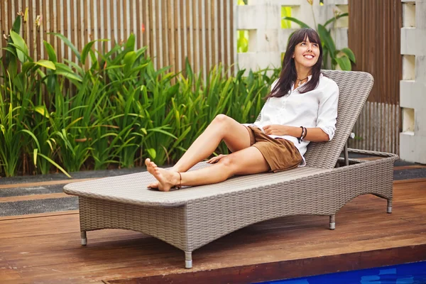 Pretty brunette woman relaxing on a lounger outdoors — Stock Photo, Image