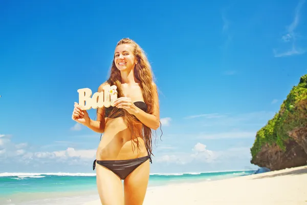 Vrouw op een strand met houten "bali" brieven — Stockfoto