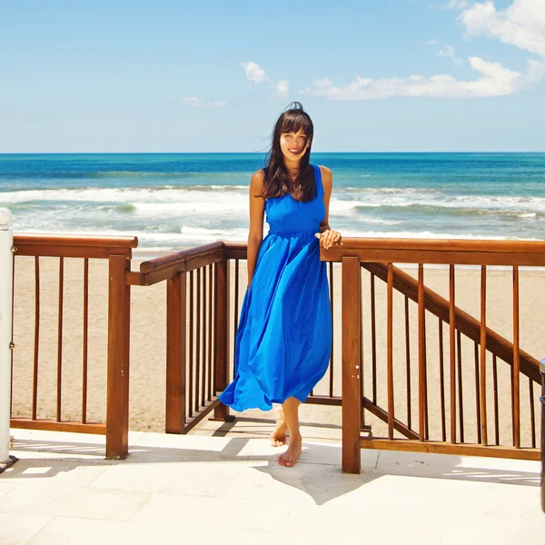 Kobieta w niebieska sukienka na plaży luksusowy — Zdjęcie stockowe