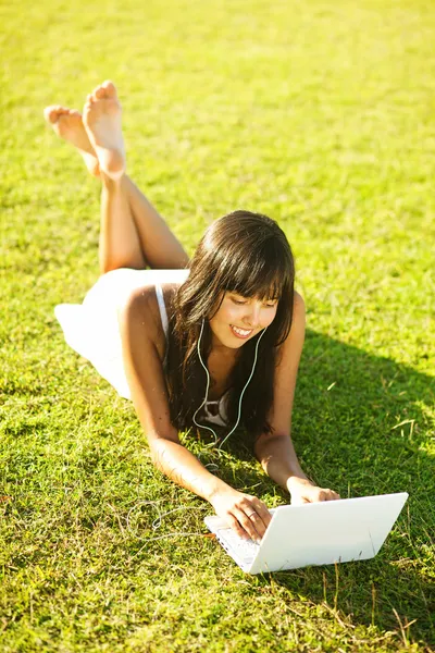 Jovem mulher em uma grama no parque ou jardim usando laptop — Fotografia de Stock