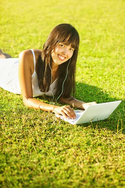 年轻女子在公园或花园里使用的便携式计算机的草地上 — 图库照片