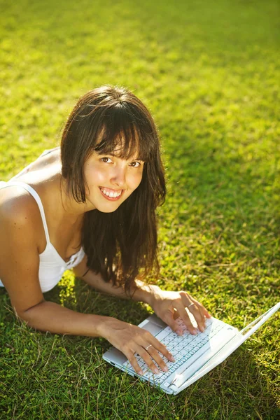 Mladá žena na trávě v parku nebo na zahradě pomocí přenosného počítače — Stock fotografie