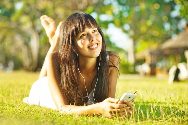 Молодая женщина слушает музыку на мобильном телефоне или в парке — стоковое фото