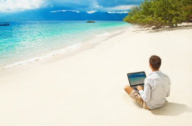 Man with laptop on colorful beach of island clipart