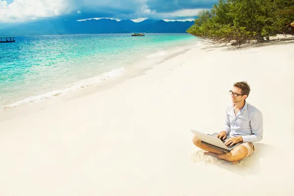 Uomo con computer portatile sulla spiaggia colorata dell'isola — Foto Stock