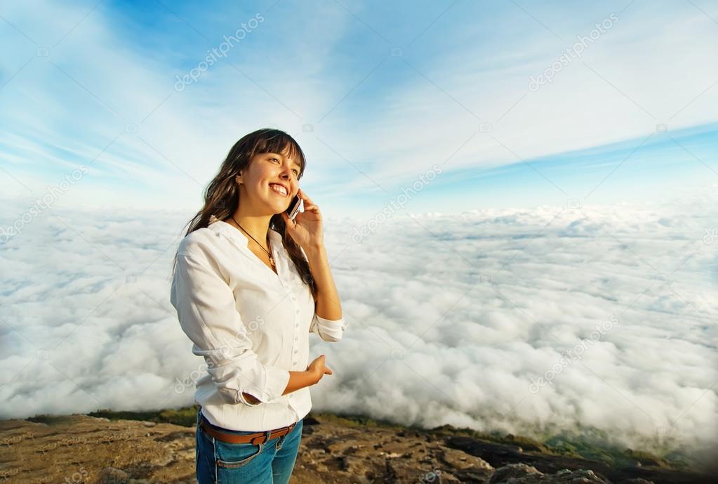 Woman talking on mobile phone in the clouds