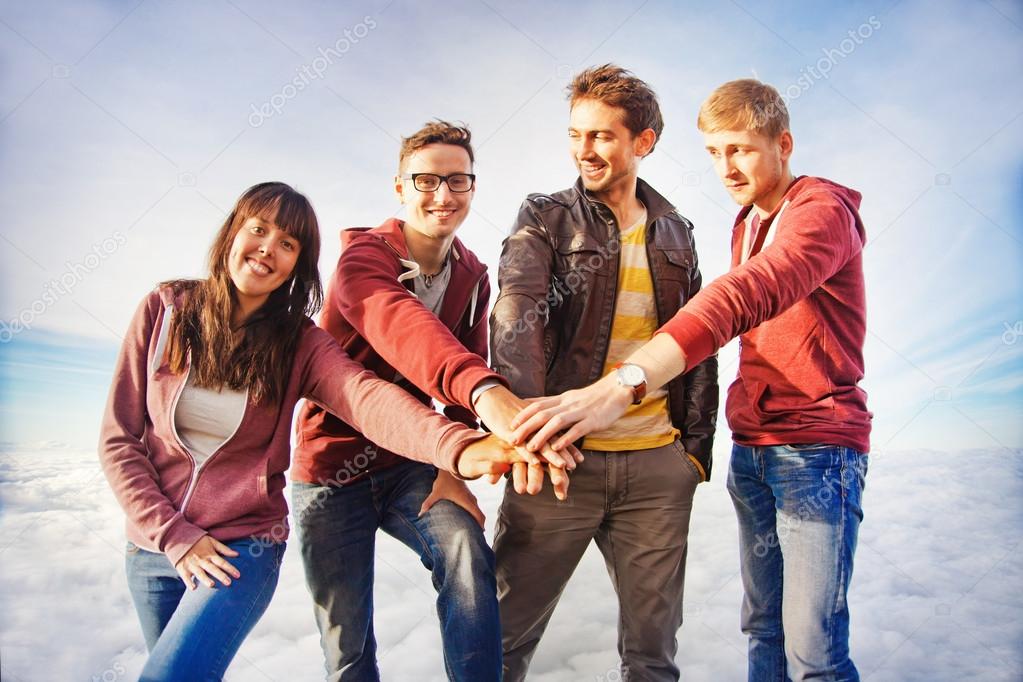Team success concept: group of people holding hands on the top of the mountain