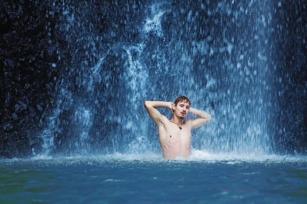 Young man refreshing in waterfall — Stock Photo, Image