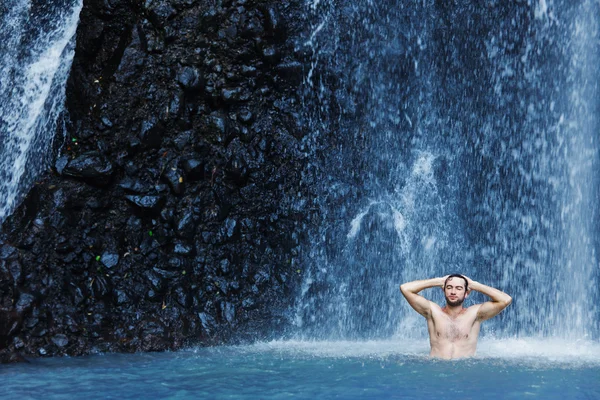 Young man refreshing in waterfall — Stock Photo, Image