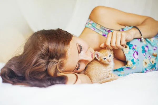 Žena uvolňující na posteli s kotě — Stock fotografie