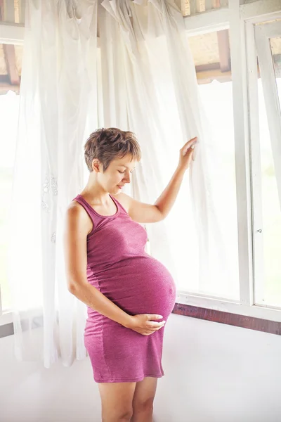 Беременная женщина у окна — стоковое фото