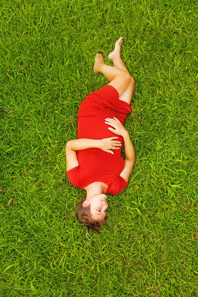 Mulher grávida deitada na grama — Fotografia de Stock