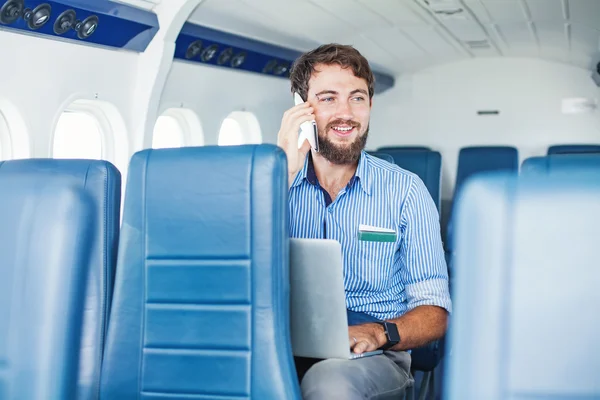 Hombre usando el teléfono y el ordenador portátil en avión — Foto de Stock