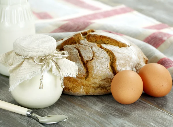 Yogur casero, leche, pan y huevos en una mesa de madera — Foto de Stock