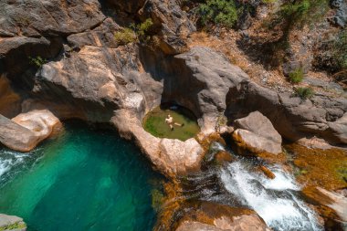 Bir erkek gezgin soğuk bir dağ nehrinde banyo yapar. Sapadere Kanyonu 'nda yüzmek ve şelale, doğa, seyahat ve tatil konsepti. Yaz güneşli bir gün. Alanya Türkiye