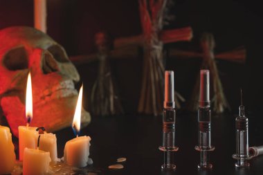 Vudu ve mumlar. Siyah arka planda kafatası ve şırıngalar. İnsan yönetimi konsepti. Zorunlu aşı. İlaçlar ve ilaçlar. Ayin ve komplo.