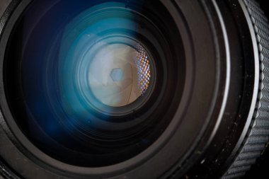 Profesyonel fotoğraf makinesi lensi. Cam parçaları, aydınlanma katmanı, açıklık yaprakları. Modern diyot lambalarının ışık yansımaları. Görsel içerik oluşturma kavramı.