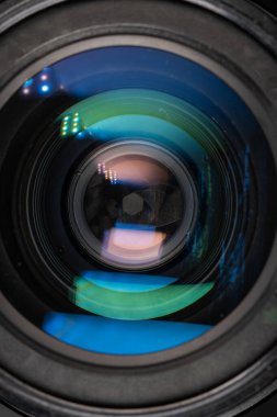 Professional camera photo lens. Details of glass, layer of enlightenment, aperture petals. Light reflections from modern diode lamps. The concept of making visual content. Vertical photo.
