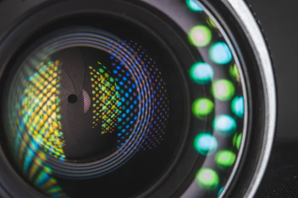 Profesyonel fotoğraf makinesi lensi. Cam parçaları, aydınlanma katmanı, açıklık yaprakları. Modern diyot lambalarının ışık yansımaları. Görsel içerik oluşturma kavramı. Sol taraf