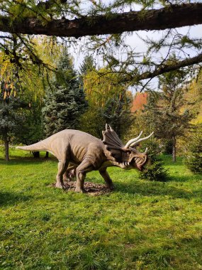 Jurassic Parkı. Ormandaki dinozorlar. Büyük hayvanlar parkta yürür. Yetişkinler ve çocuklar için eğlence ve eğlence kavramı. Dikey fotoğraf. Triceratops Ceratopsianları