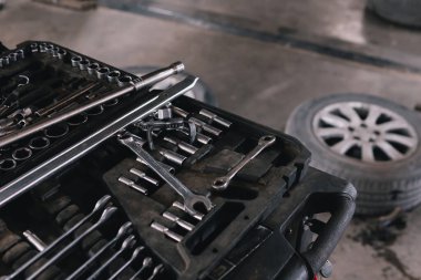 Close up, car repair tool. Car service center. Vehicle raised on lift at maintenance station. Auomobile repair and check up. Wheel. Selective focus.