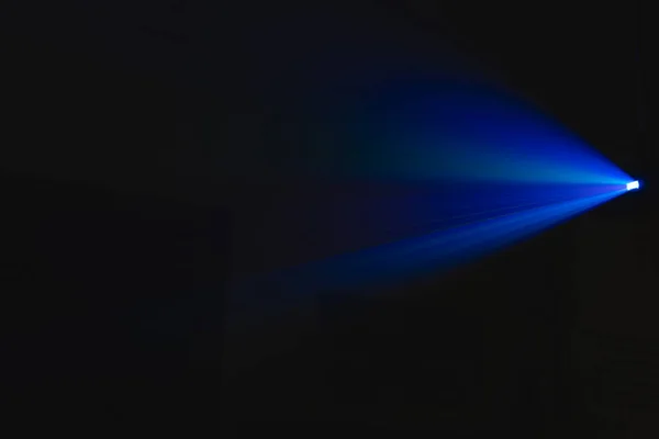 projector spotlight blue color , smoke texture background . light beam screening and glowing for movie cinema and film multimedia production in dark black room at night . wide lens showing, copy space