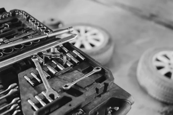 Close up, car repair tool. Car service center. Vehicle raised on lift at maintenance station. Auomobile repair and check up. Wheel. Selective focus. Black and white.