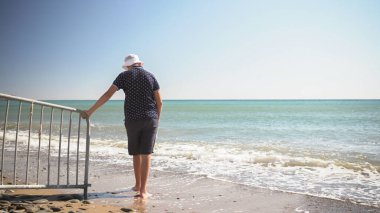 Adam plajın kıyısında üzgün. Bir şey düşünüyordu.