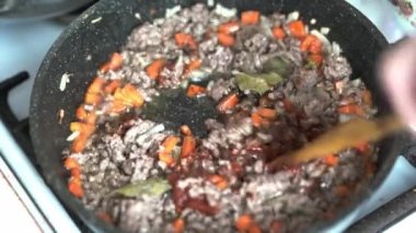 Lazanya için bolonez sosu hazırlıyorum. Domates ezmesi ve baharatları sebzeli, havuçlu, soğanlı, defne yapraklı kıymaya ekliyorum. Bir spatula kullanarak, kızgın tavayı yağ ve yağla karıştır..