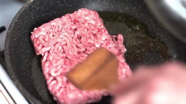 Minced meat is laid out on a hot frying pan with boiling oil for frying and sauce preparation. With a frying pan spatula, the meat is stirred in a hot frying pan. — Stock Video