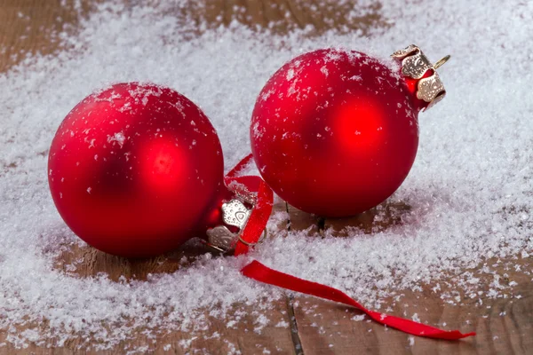 Bolas vermelhas com flocos de neve, em fundo de madeira — Fotografia de Stock