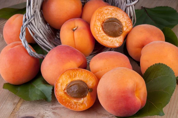 Aprikoser med blad på trä bakgrund — Stockfoto