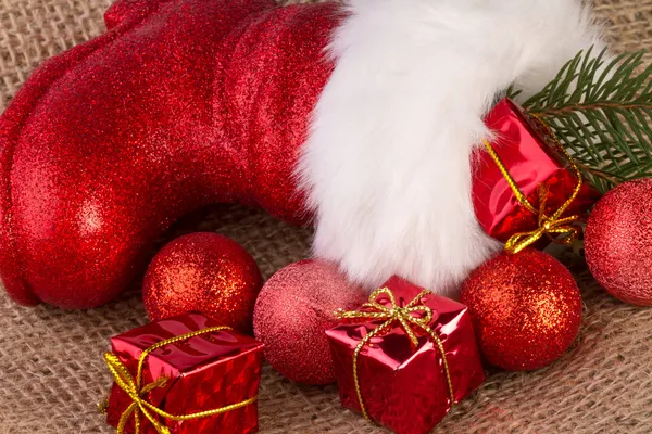 Santa claus laarzen met geschenken op jute achtergrond — Stockfoto