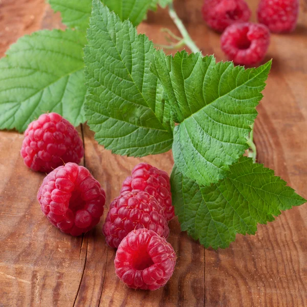 Raspberries with leafs on wooden background — Stock Photo, Image