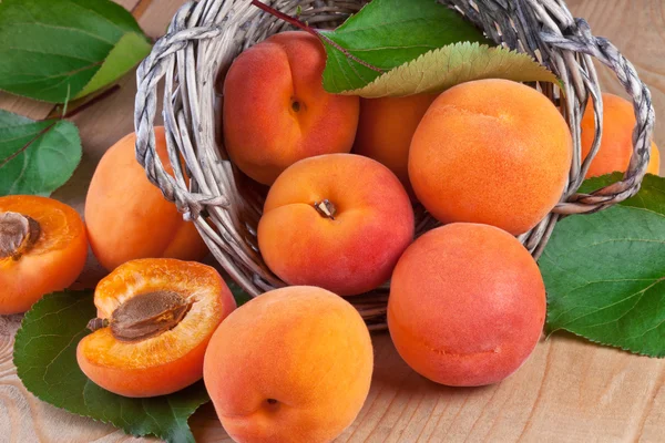 Verse abrikozen met bladeren op houten achtergrond — Stockfoto