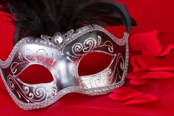Venetiaanse masker en harten op rode achtergrond — Stockfoto