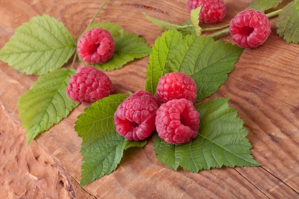 Raspberries with leafs on wooden background — Stock Photo, Image