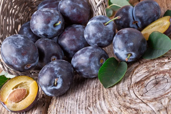 Ciruelas con hojas sobre fondo de madera — Foto de Stock