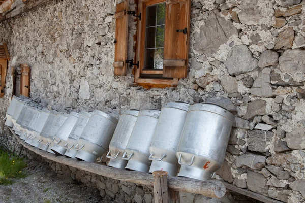 Vieilles canettes de lait sur une étagère dans une cabane alpine — Photo