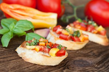 Bruschetta ile domates, kırmızı biber, sarımsak, fesleğen ahşap arka plan üzerinde