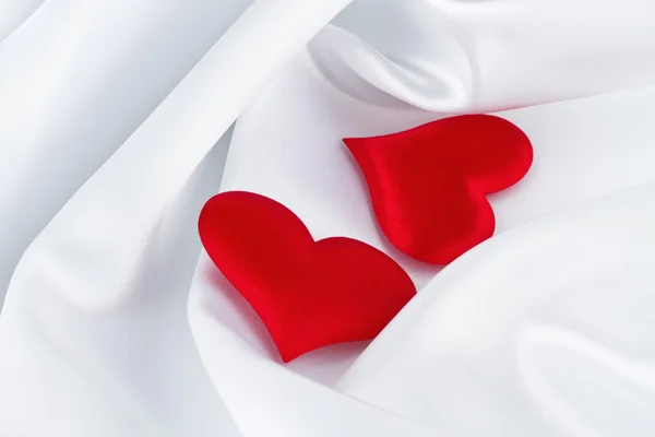 Röda hjärtan på vit siden — Stockfoto