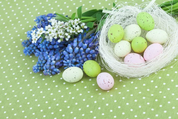 Osterdekoration mit Frühlingsblumen und Eiern auf grüner Tupfen-Tischdecke — Stockfoto