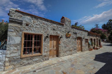 DATCA, TURKEY - 05.Eyll .2021 . Ortaçağ sokak manzarası. Hediyelik eşya dükkanı ve kafesi olan eski bir taş bina. Türk kırsalında. Çakıl taşı, taş bina, dekorasyon, yaz mevsimi, mavi gökyüzü..