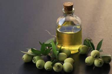 Cam bir kapta Myrtle yağı. Mersin yağıyla, mersin üzümleri ile izole edilmiş gri arka planda.