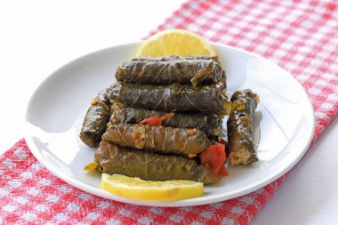 Dolma, pirinç ile doldurulmuş üzüm yaprakları ve beyaz bir tabakta et, ön manzara.