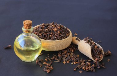 Baharat karanfili cam şişede gerekli yağ ve koyu ahşap arka planda kuru karanfil