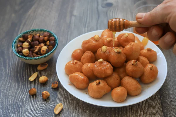 A bowl of Lokma (Turkish), loukoumades (Greeek ) with other names in other languages, are pastries made of leavened and deep fried dough, soaked in syrup or honey, sometimes coated with cinnamon