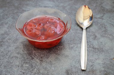 Küçük bir kasede olgun çileklerle serinletici çilek kompostosu.